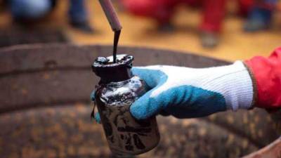 Un empleado de una empresa mexicana toma una muestra de petróleo extraído.