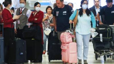 Miembros de una tripulación de vuelo de Cathay Pacific Airways (L), con máscaras protectoras, se paran en la terminal internacional después de llegar en un vuelo desde Hong Kong al Aeropuerto Internacional de Los Ángeles (LAX) el 28 de febrero. 2020 en Los Angeles, California. La Organización Mundial de la Salud (OMS) ha elevado el nivel de riesgo global de coronavirus a 'muy alto'. Mario Tama / Getty Images / AFP