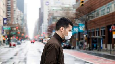 Un hombre con una máscara protectora cruza una avenida tranquila en Nueva York. Foto EFE