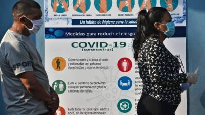 People wear face masks as they keep the safety distance while queuing to enter the Honduran Social Security Institute (IHSS) in Tegucigalpa on April 13, 2020. - 393 cases of COVID-19 and 25 deaths were reported in Honduras so far. (Photo by ORLANDO SIERRA / AFP)