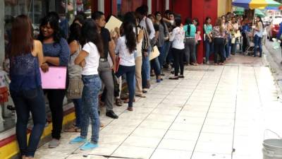 Jóvenes hacen fila fuera de una tienda de ropa que está en el centro de la ciudad.