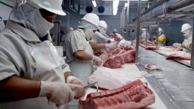 Industria. Empleados cortando y preparando la carne de cerdo antes de ser distribuida. Imagen de archivo.