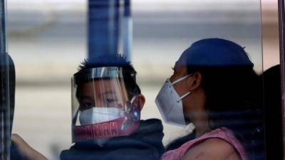 Un niño fue registrado este lunes al usar careta y mascarilla, al trasladarse junto a una mujer en un bus urbano, en Tegucigalpa (Honduras). EFE