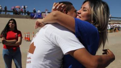 Una pareja de inmigrantes se abrazan en la frontera entre EEUU y México en un evento organizado por una ONG que logró que abrieran la valla por tres minutos./AFP.