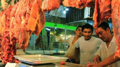 Tres jóvenes trabajan en un puesto de carne en el mercado El Dandy de San Pedro Sula. Foto: Cristina Santos