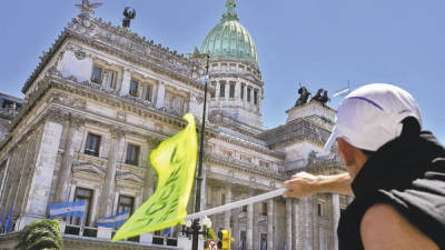 Un hombre flamea una bandera frente al Congreso de Argentina.