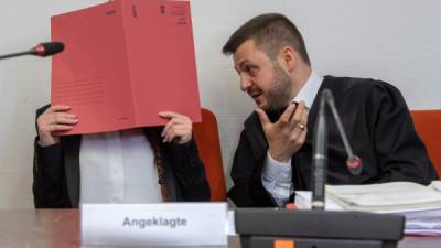 La acusada Jennifer W esconde su rostro detrás de una carpeta y se sienta junto a su abogado Ali Aydin. AFP