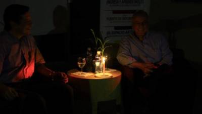 José H. Bográn y Julio Escoto a la luz de una vela, que alumbró la sala durante el conversatorio.