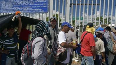 Migrantes hondureños permanecen en el puente internacional Rodolfo Robles, que cruza el Río Suchiate, que une a México con Guatemala. EFE