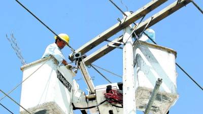 Un empleado de la estatal eléctrica trabaja en la reparación del cableado en un poste de energía.
