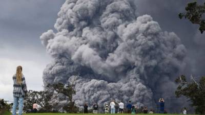 HAWAII VOLCANOES NATIONAL PARK, HI - MAY 15: People watch at a golf course as an ash plume rises in the distance from the Kilauea volcano on Hawaii's Big Island on May 15, 2018 in Hawaii Volcanoes National Park, Hawaii. The U.S. Geological Survey said a recent lowering of the lava lake at the volcano's Halemaumau crater 'has raised the potential for explosive eruptions' at the volcano. Mario Tama/Getty Images/AFP== FOR NEWSPAPERS, INTERNET, TELCOS & TELEVISION USE ONLY ==