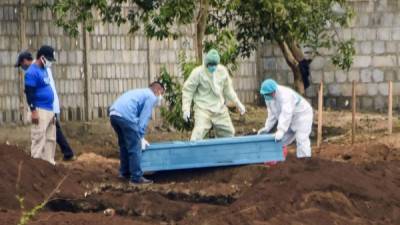 Empleados sanitarios sepultan a un hombre fallecido por 'neumonía viral' en Managua./AFP.