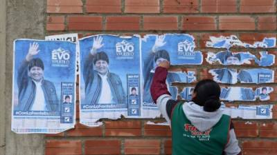 Una mujer quita los carteles del Evo Morales de Bolivia de la pared de una casa en El Alto el 11 de noviembre de 2019, un día después de la renuncia del líder izquierdista como presidente. Morales anunció su renuncia el domingo, cediendo después de tres semanas de protestas a veces violentas por su disputada reelección después de que el ejército y la policía retiraron su respaldo. / AFP / Aizar RALDES