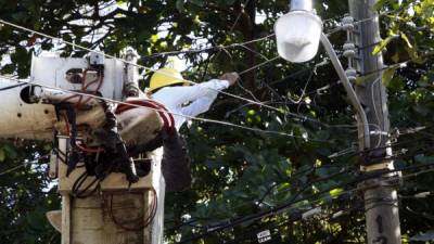 Un empleado de la Enee trabaja en la reparación de una de las lámparas de la colonia. Foto: Jorge Gonzales