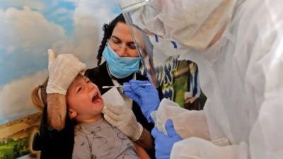Un niño es sometido a una prueba de hisopo para coronavirus. AFP