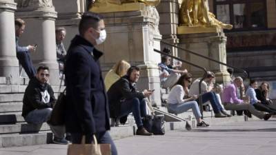 Personas sentadas al sol en los escalones del Royal Dramatic Theatre en Estocolmo. Foto: AFP