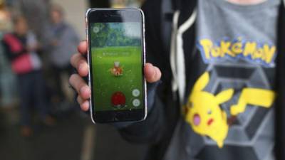 Un aficionado con una camiseta del mítico personaje Pikachu muestra en la pantalla de su móvil el juego 'Pokémon Go' cerca del Teatro de la Ópera de Sídney, Nueva Gales del Sur, Australia. EFE
