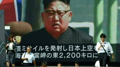 TOPSHOT - Pedestrians walk in front of a large video screen in Tokyo broadcasting a news report showing North Korean leader Kim Jong-Un, following a North Korean missile test that passed over Japan on September 15, 2017.North Korea fired a ballistic missile over Japan and into the Pacific on September 15, responding to new UN sanctions with what appeared to be its furthest-ever missile flight amid high tensions over its weapons programmes. / AFP PHOTO / Toru YAMANAKA