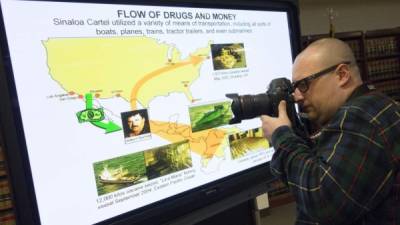 A photographer takes photos of the display used at the press conference discussing the extradition of Joaquin 'El Chapo' Guzman on January 20, 2017 in New York.Joaquin 'El Chapo' Guzman, one of the world's most notorious criminals, appeared before a US court on Friday to answer drug trafficking, firearms and conspiracy charges that could see him jailed for life. / AFP PHOTO / Don EMMERT