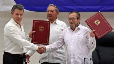 El delegado de las FARC en Cuba, Rodrigo Londoño Echeverri, alias 'Timochenko', el presidente de Colombia, Juan Manuel Santos junto a el presidente de Cuba, Raúl Castro, sostienen en sus manos el acuerdo de paz entre el Gobierno colombiano y las FARC. EFE