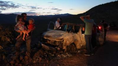 TOPSHOT - CORRECTION - Members of the LeBaron family look at the burned car where part of the nine murdered members of the family were killed and burned during an ambush in Bavispe, Sonora mountains, Mexico, on November 5, 2019. - US President Donald Trump offered on November 5 to help Mexico 'wage war' on its cartels after three women and six children from an American Mormon community were murdered in an area notorious for drug traffickers. (Photo by Herika MARTINEZ / AFP) / The erroneous mention appearing in the metadata of this photo has been modified in AFP systems in the following manner: byline should read [Herika MARTINEZ] instead of [STRINGER]. Please immediately remove the erroneous mention from all your online services and delete it from your servers. If you have been authorized by AFP to distribute it to third parties, please ensure that the same actions are carried out by them. Failure to promptly comply with these instructions will entail liability on your part for any continued or post notification usage. Therefore we thank you very much for all your attention and prompt action. We are sorry for the inconvenience this notification may cause and remain at your disposal for any further information you may require.