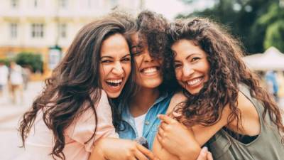 Three best friends hugging each other in the city.