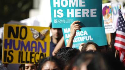 A woman holds up a fist and a sign referencing 'dreamers', a term used for undocumented young people who were brought to the United States as children, as a coalition of activist groups and labor unions participate in a May Day march for workers' and human rights in Los Angeles, California on May 1, 2021. (Photo by DAVID MCNEW / AFP)