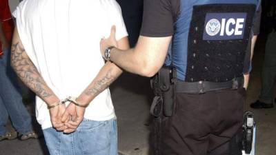 Un agente de la Oficina de Inmigración y Aduanas (ICE) de Miami lleva arrestado a un presunto miembro de la pandilla ''Mara Salvatrucha'' (MS-13) que fue detenido en Lake Worth, en el sureste del estado de Florida (EEUU). EFE/Archivo