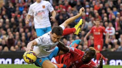 Mario Balotelli cae al césped junto a Alex Bruce, del Hull City.