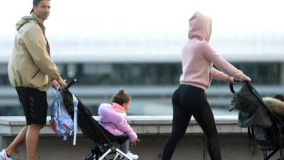 Cristiano Ronaldo (L) and his partner Georgina Rodriguez push two strollers as they have a walk with their children in Funchal on March 28, 2020. (Photo by HELDER SANTOS / AFP)