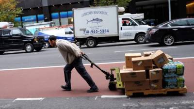 Un repartidor jala mercancías de electrónica en una calle de Nueva York.