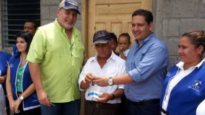 Genaro Mendoza, centro, recibe de autoridades del Gobierno la llave de su casa.