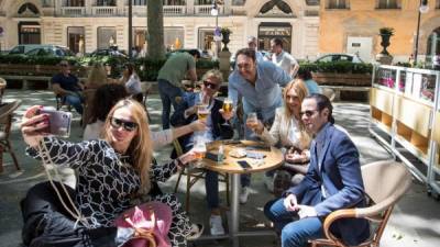 People take a selfie as they share a toast at a terrace bar in Palma de Mallorca on May 11, 2020, as Spain moved towards easing its strict lockdown in certain regions. - Spaniards returned to outdoor terraces at cafes and bars as around half of the country moved to the next phase of a gradual exit from one of Europe's strictest lockdowns (Photo by JAIME REINA / AFP)