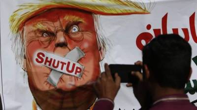 Un partidario de la ONG islamista Jamaat-ud-Dawa (JuD) toma una fotografía de una pancarta contra el presidente estadounidense, Donald Trump, durante una protesta contra la decisión del Gobierno de prohibir donaciones a la organización, en Karachi, Pakistán, el pasado 2 de enero. EFE