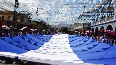 Una gigantesca bandera de Honduras cargada por los alumnos del San Isidro. Fotos: Javier Rosales
