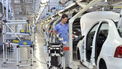 Un empleado de una fábrica de la Volkswagen verifica las partes de un vehículo en pleno armado.