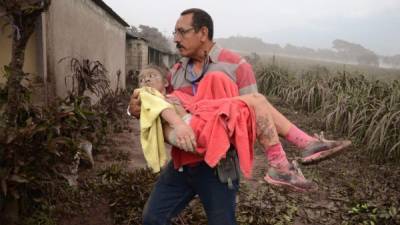 GU7080. EL RODEO (GUATEMALA), 03/06/2018.- Un hombre ayuda a una niña afectada en El Rodeo, Escuintla (Guatemala) hoy, domingo 3 de junio de 2018, luego de la erupción del volcán de Fuego, que ha dejado al menos 25 muertos, 20 heridos y más de 1,7 millones de personas afectadas. EFE/NOE PÉREZ