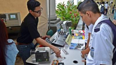 Un alumno de la carrera de Ingeniería Eléctrica enseña a los visitantes el funcionamiento de un proyecto.