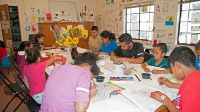 Un grupo de niños migrantes y algunos padres participan en una clase de arte del albergue para familias migrantes en el antiguo Monasterio Benedictino en la ciudad de Tucson. EFE/Archivo