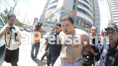 Momento en que la Policía de Honduras saca del edificio Metrópolis a Rigoberto Andrés Paredes Vélez. Leonel Sauceda, derecha, dijo que el joven admitió cometer el crimen contra el abogado Eduardo Montes.