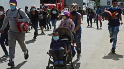 Los migrantes hondureños corren luego de romper una cerca policial y entrar a Guatemala desde Corinto, Honduras. AFP