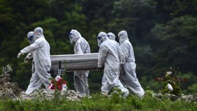 Vestidos con trajes protectores, un grupo de personas cargan el féretro de una presunta víctima de coronavirus en un cementerio de Tegucigalpa, Honduras.