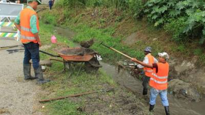 Obreros municipales trabajan en la limpieza de un canal de aguas lluvias.