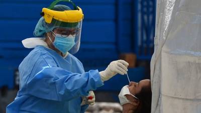 A health worker collects a nasal swab sample from a patient to be tested for COVID-19 in one of the four tents installed to treat cases of the new coronavirus, at the parking lot of the School Hospital in Tegucigalpa, on June 9, 2020. - Honduras reopens its business activities, cautiously, after almost three months of confinement, though, according to experts, at the worst time to do so due to the rapid rise of the coronavirus and at high risk of closing again. (Photo by ORLANDO SIERRA / AFP)