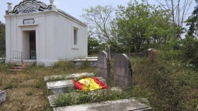 Una bandera de España colocada por unos turistas que visitaron el cementerio militar franco-español de Danang, en el centro de Vietnam, cubre unas tumbas de soldados españoles que lucharon en la guerra de la Cochinchina en el siglo XIX. EFE