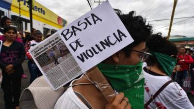 Una mujer sostiene un cartel que dice 'Basta de violencia' mientras participa en un ritual en memoria de las mujeres asesinadas en Honduras. AFP