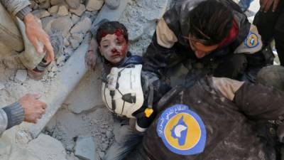 Voluntarios, conocidos como Cascos Blancos, en el rescate de un niño en Alepo. Fotos: AFP