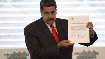 Venezuelan President Nicolas Maduro, shows the document issued by the National Electoral Council (CNE) that proclaims him as re-elected President for the term 2019-2025, at the CNE headquarters in Caracas on May 22, 2018. Venezuela said Tuesday it was the victim of a 'political and financial lynching' after the United States tightened sanctions on Caracas over Nicolas Maduro's re-election. / AFP PHOTO / Federico PARRA