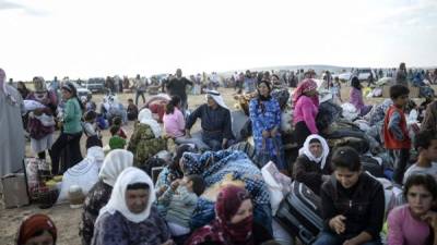 Un grupo de kurdos sirios espera cerca de la frontera huyendo de las amenazas del Estado Islámico.