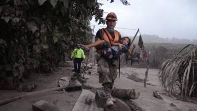 -FOTODELDIA- GU7080. EL RODEO (GUATEMALA), 03/06/2018.- Un trabajador de los equipos de rescate de Guatemala ayuda a una niña en El Rodeo, Escuintla (Guatemala) hoy, domingo 3 de junio de 2018, luego de la erupción del volcán de Fuego, que ha dejado al menos 25 muertos, 20 heridos y más de 1,7 millones de personas afectadas. EFE/NOE PÉREZ